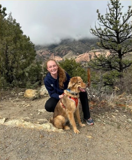 Trainer with a golden dog on a mountain trail